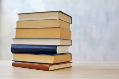 Ahşap arka planda bir yığın kitap, kütüphanenin arka planına karşı bir yığın kitap, kütüphanenin önünde bir yığın kitap, ahşap masa üzerine kitaplar.