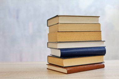 Ahşap arka planda bir yığın kitap, kütüphanenin arka planına karşı bir yığın kitap, kütüphanenin önünde bir yığın kitap, ahşap masa üzerine kitaplar.