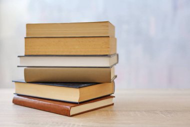 Ahşap arka planda bir yığın kitap, kütüphanenin arka planına karşı bir yığın kitap, kütüphanenin önünde bir yığın kitap, ahşap masa üzerine kitaplar.