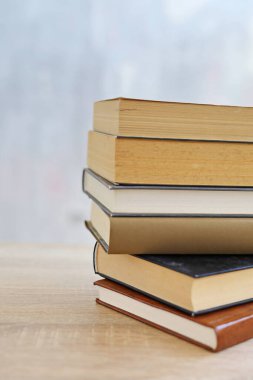 Ahşap arka planda bir yığın kitap, kütüphanenin arka planına karşı bir yığın kitap, kütüphanenin önünde bir yığın kitap, ahşap masa üzerine kitaplar.