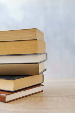 Ahşap arka planda bir yığın kitap, kütüphanenin arka planına karşı bir yığın kitap, kütüphanenin önünde bir yığın kitap, ahşap masa üzerine kitaplar.