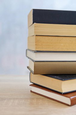 Ahşap arka planda bir yığın kitap, kütüphanenin arka planına karşı bir yığın kitap, kütüphanenin önünde bir yığın kitap, ahşap masa üzerine kitaplar.