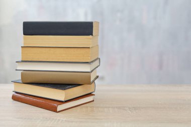 Ahşap arka planda bir yığın kitap, kütüphanenin arka planına karşı bir yığın kitap, kütüphanenin önünde bir yığın kitap, ahşap masa üzerine kitaplar.