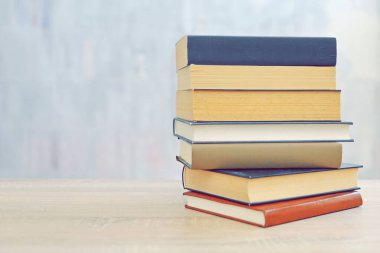 Ahşap arka planda bir yığın kitap, kütüphanenin arka planına karşı bir yığın kitap, kütüphanenin önünde bir yığın kitap, ahşap masa üzerine kitaplar.