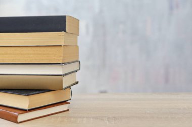 Ahşap arka planda bir yığın kitap, kütüphanenin arka planına karşı bir yığın kitap, kütüphanenin önünde bir yığın kitap, ahşap masa üzerine kitaplar.