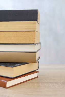 Ahşap arka planda bir yığın kitap, kütüphanenin arka planına karşı bir yığın kitap, kütüphanenin önünde bir yığın kitap, ahşap masa üzerine kitaplar.