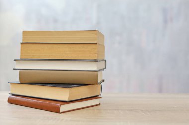 Ahşap arka planda bir yığın kitap, kütüphanenin arka planına karşı bir yığın kitap, kütüphanenin önünde bir yığın kitap, ahşap masa üzerine kitaplar.