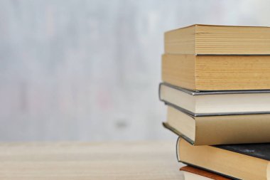 Ahşap arka planda bir yığın kitap, kütüphanenin arka planına karşı bir yığın kitap, kütüphanenin önünde bir yığın kitap, ahşap masa üzerine kitaplar.