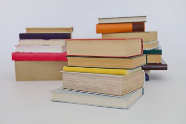 Beyaz arkaplan üzerine bir yığın kitap, kütüphanenin arka planına karşı bir yığın kitap, kütüphanenin önünde bir yığın kitap, ahşap masa üzerine kitaplar.