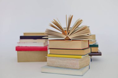 Beyaz arkaplan üzerine bir yığın kitap, kütüphanenin arka planına karşı bir yığın kitap, kütüphanenin önünde bir yığın kitap, ahşap masa üzerine kitaplar.