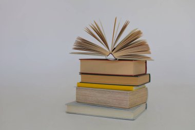 Beyaz arkaplan üzerine bir yığın kitap, kütüphanenin arka planına karşı bir yığın kitap, kütüphanenin önünde bir yığın kitap, ahşap masa üzerine kitaplar.