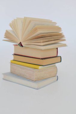 Beyaz arkaplan üzerine bir yığın kitap, kütüphanenin arka planına karşı bir yığın kitap, kütüphanenin önünde bir yığın kitap, ahşap masa üzerine kitaplar.