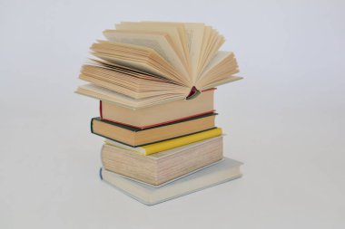 Beyaz arkaplan üzerine bir yığın kitap, kütüphanenin arka planına karşı bir yığın kitap, kütüphanenin önünde bir yığın kitap, ahşap masa üzerine kitaplar.