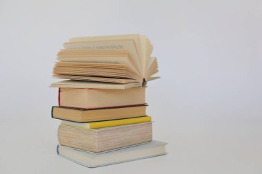 Beyaz arkaplan üzerine bir yığın kitap, kütüphanenin arka planına karşı bir yığın kitap, kütüphanenin önünde bir yığın kitap, ahşap masa üzerine kitaplar.