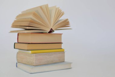 Beyaz arkaplan üzerine bir yığın kitap, kütüphanenin arka planına karşı bir yığın kitap, kütüphanenin önünde bir yığın kitap, ahşap masa üzerine kitaplar.