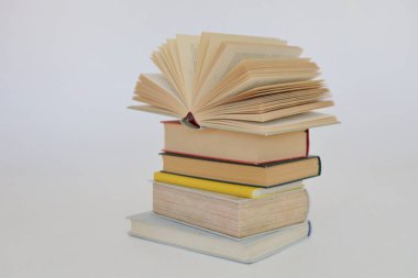 Beyaz arkaplan üzerine bir yığın kitap, kütüphanenin arka planına karşı bir yığın kitap, kütüphanenin önünde bir yığın kitap, ahşap masa üzerine kitaplar.