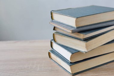 Bulanık arka plana karşı ahşap masadaki kitap yığını