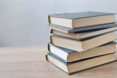 Tahta bir masanın üzerinde bir yığın kitap..