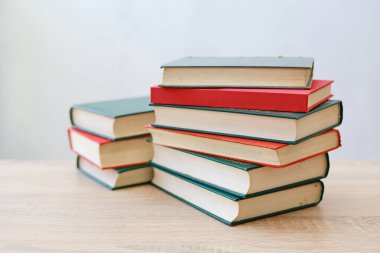 Gri arkaplana karşı ahşap masadaki kitap yığını