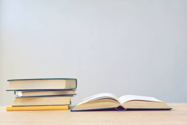 Tahta bir masanın üzerinde bir yığın kitabın olduğu açık bir kitap.