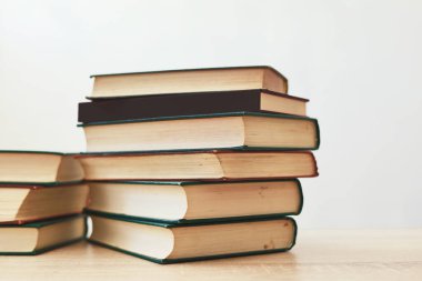 Tahta masadaki kitap yığını beyaz arka plana karşı. Metin için boşluk