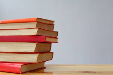 Ahşap masanın üzerinde bir yığın kitap ve kırmızı kalemler.