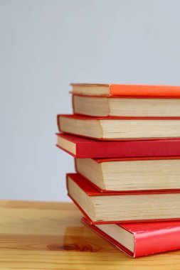Kırmızı duvara karşı ahşap masanın üzerinde yığınla kitap. Metin için boşluk