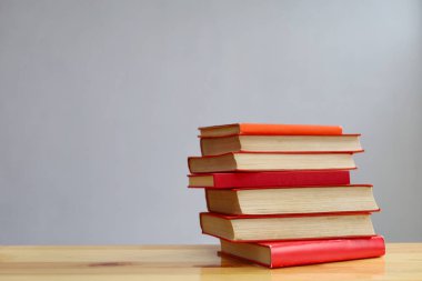Gri duvara karşı ahşap masadaki kitap yığını