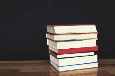 Bulanık arkaplana karşı siyah tablo üzerinde kitap yığını