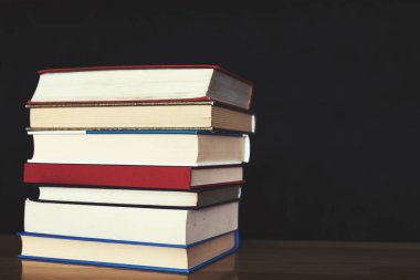 Masadaki kitap yığınına karşılık kopya alanı olan koyu bir arkaplan.