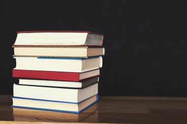 Tahta masadaki kitap yığını.