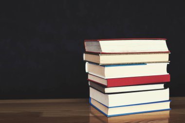 Kütüphanedeki ahşap masada yığınla kitap.