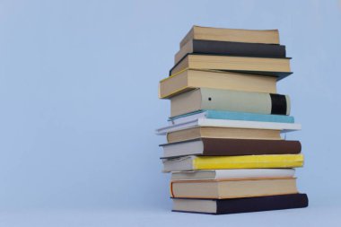 Masada bir yığın kitap, kütüphanenin arka planına karşı bir yığın kitap, kütüphanenin önünde bir yığın kitap, ahşap masa üzerine kitaplar.