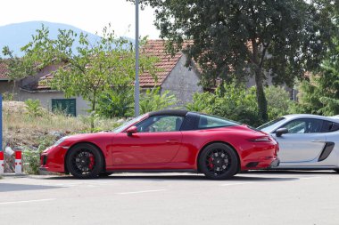 Kırmızı ve beyaz araba yolda.