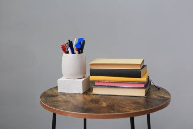 Masada gri arkaplana karşı kitap ve kalem yığını