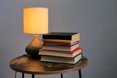 Kitap ve lamba yığını gri duvar arkaplanındaki masada