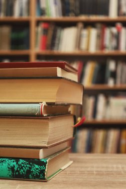 Ahşap rafta bir yığın kitap ve kütüphane arkaplanının önündeki ahşap masanın üzerinde bir yığın bardak. eğitim ve bilgi kavramı.