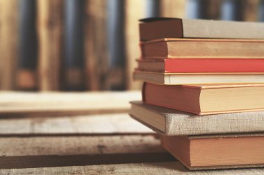 Kütüphanedeki ahşap masada yığınla kitap.