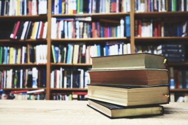 Kütüphanedeki ahşap masa üzerinde kitap yığını, eğitim konsepti