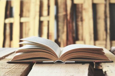 Dağ evindeki ahşap bir masanın üzerinde açılmış eski bir kitap. Dağda kış tatilinin tadını çıkarıyorum. Kitap, ahşap masadaki kitaplar.