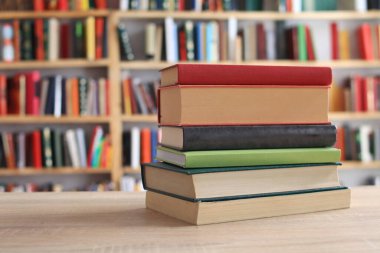 Kütüphanedeki ahşap masada yığınla kitap.