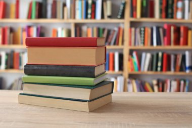 Kütüphanedeki ahşap masada yığınla kitap. Metin için boşluk