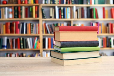 Bulanık kütüphane arkaplanının yakınındaki masada kitap yığını. Metin için boşluk