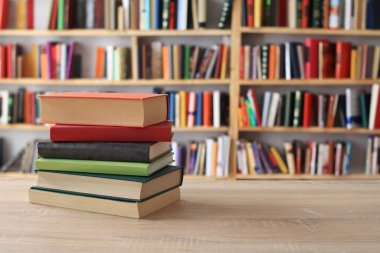 Kütüphanedeki ahşap masada yığınla kitap.