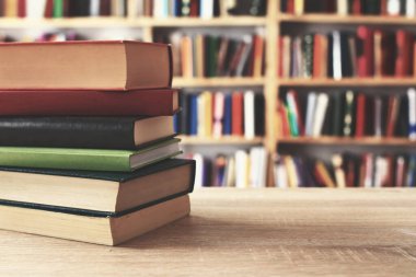 Arkaplanda kütüphane yığını olan kitaplar
