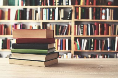 Kütüphanede ahşap masa üzerinde kitap yığını, metin için boşluk
