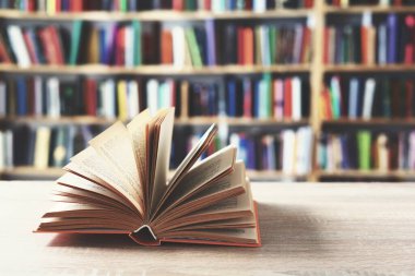 Tahta masanın üzerinde kitap yığını olan açık bir kitap.