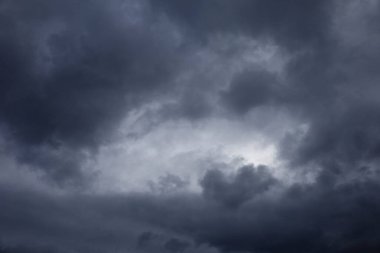 Gökyüzündeki kara bulutlar kalın, gri yağmur bulutlarıyla kaplı karanlık gökyüzü güneşi neredeyse tamamen gizliyor. Hava ağır ve nemli ve bulutlar daha başlamamış bir fırtınayı tehdit ederek alçaktan sarkmış gibi görünüyor.. 