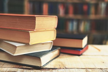 Kütüphanedeki ahşap masada yığınla kitap.