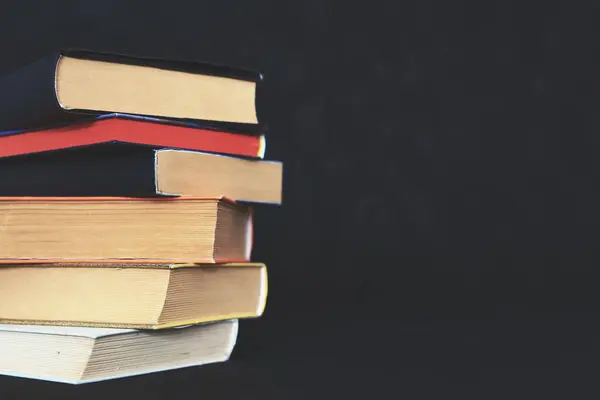 stack books in library. stack of old books. Paper publications from the old library. Dark background.Old books in vintage library. History, education concept. Hand reaches for and pulls classic book from library shelf; vintage look.